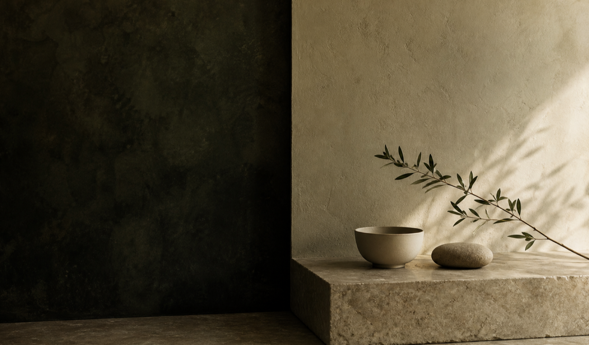 A quiet bathroom still life with stone, ceramic, and a single branch